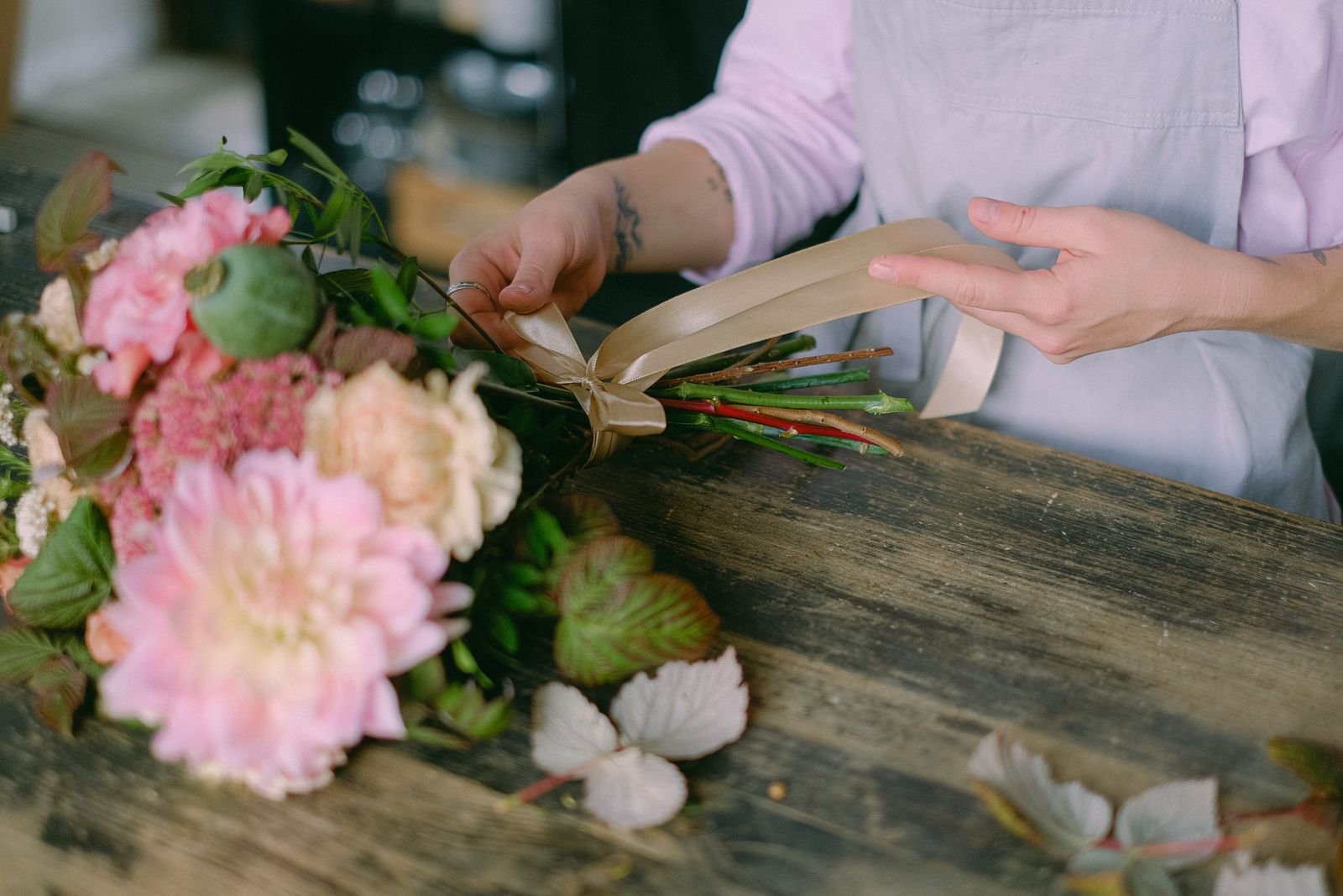 A florist’s hands arranging seasonal stems in the studio